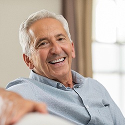 Older man smiling while sitting on couch