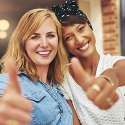 Two smiling women giving thumbs up